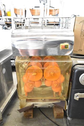 Stainless steel commercial countertop citrus juicer, 115 volts, 1 phase, features orange squeezing mechanism, on/off switch visible.