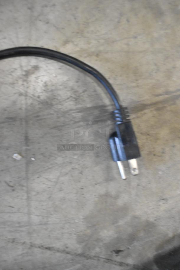 Close-up image of a black electrical plug for a stainless steel commercial countertop citrus juicer.