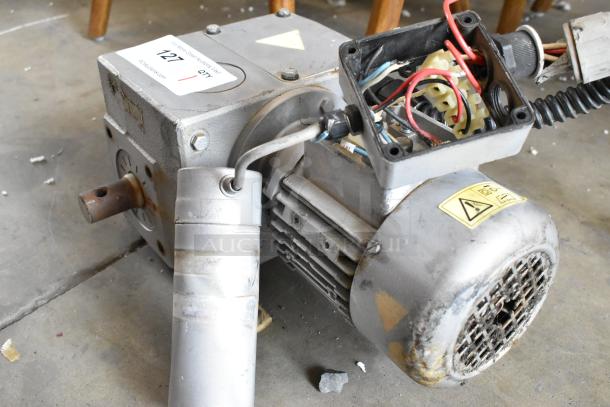 Industrial motor with visible wiring, metal casing, and wear marks, features caution labels; condition shows heavy usage.