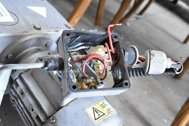 Industrial motor with exposed wiring, features metal housing and a visible warning label. Used condition.