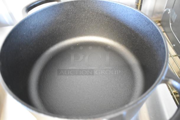 Brand new cast iron Dutch oven, scratch and dent, black, with two handles, visible interior texture.