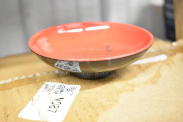Brand new red and black bowl on cardboard, featuring tags and markings.