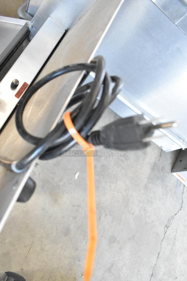 Metal countertop sealing station with power cord and orange zip tie. Operates on 115 Volts, 1 Phase. Slight wear visible.