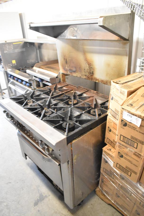 Southbend stainless steel commercial gas range with 6 burners, oven, overshelf, backsplash, on casters; visible wear.