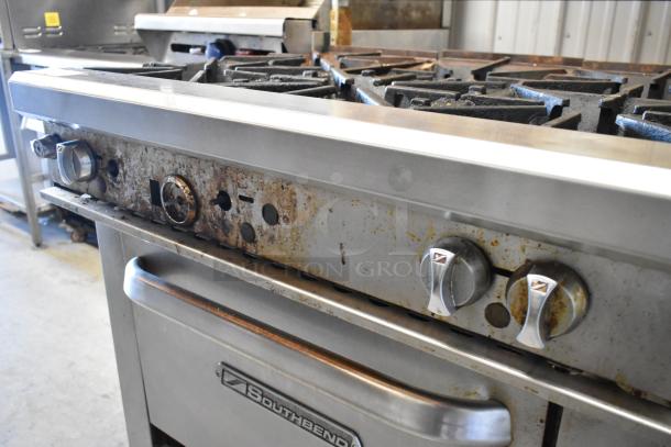 Southbend stainless steel commercial gas 6-burner range with oven, over shelf, backsplash, and commercial casters. Visible wear.