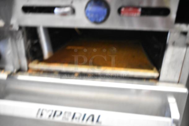 Imperial stainless steel commercial gas range with 6 burners, flat top griddle, 2 ovens, and back splash on casters.