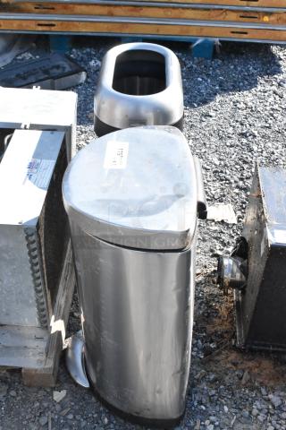 Two metal trash cans, one with a step pedal, showing minor wear. Tag on front indicates "179"; second can in background.