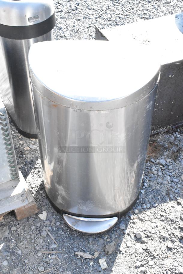 Stainless steel trash cans, round and semi-round, with foot pedals, some surface wear visible.