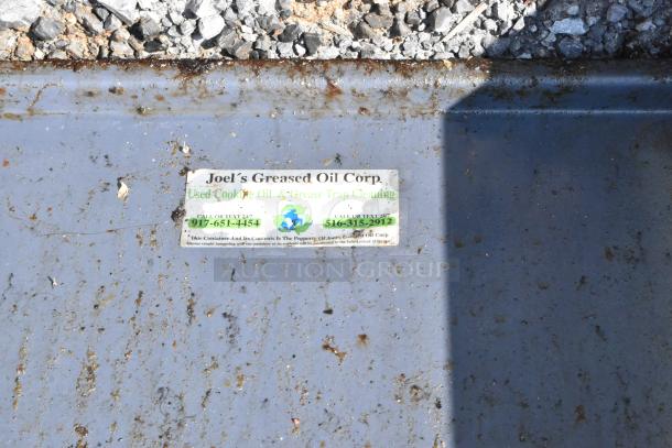 Metal commercial grease trap with visible rust and dirt, labeled "Joel's Greased Oil Corp" for used oil and grease cleaning.