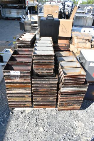 Lot of metal 4-loaf baking pans, stacked outdoors, used condition with visible rust, numbered tag attached.