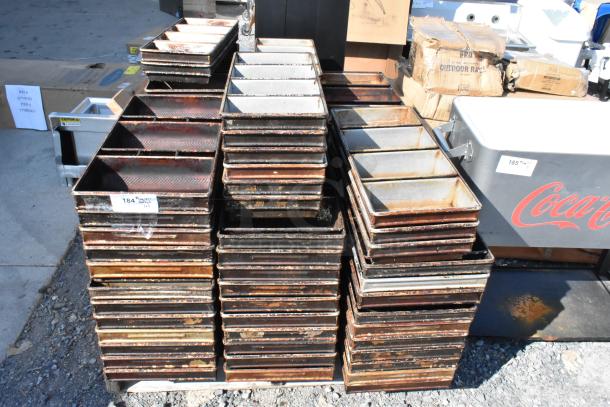 Lot of metal loaf baking pans, stacked and used. Visible labels indicate item numbers. Ideal for bulk purchase.