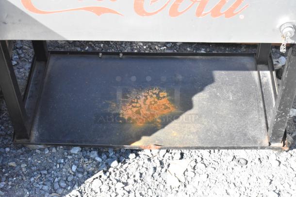 Coca Cola Poly Portable Ice Bin, features rust and wear, black frame, partial Coca Cola logo visible.