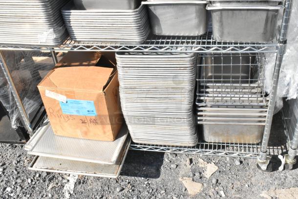 Chrome 4-tier wire shelving unit with stainless steel bins and baking pans, includes a cardboard box labeled "Rings". Buyer dismantles.