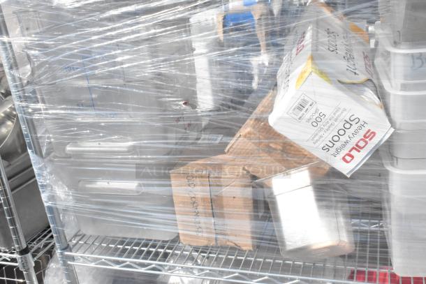 Chrome finish 4-tier wire shelving unit with poly drop in bins, ingredient bin, and poly bins. Contents wrapped in plastic.