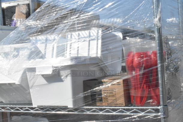 Chrome finish 4-tier wire shelving unit with contents, including ingredient bins and red utensils, wrapped in plastic.