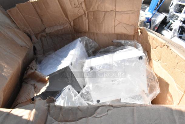 Cardboard box with new, scratch and dent metal components, including stainless steel table parts and Regency posts. Items in packaging.