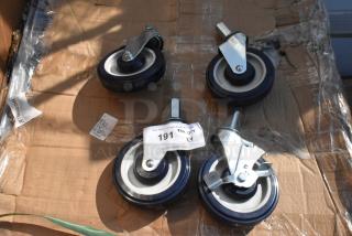 Lot of 4 brand new commercial casters, slight scratches and dents, metal brackets, black and white wheels, auction tag visible.