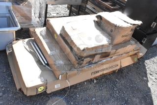 Boxes labeled "ITEM#109RACKECON" containing scratch and dent patio stove and pan rack items on pallets.