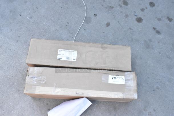 Two brand new Vollrath Lid Saver LS03IB-2B boxes marked VOL5T, showing minor scratches and dents.