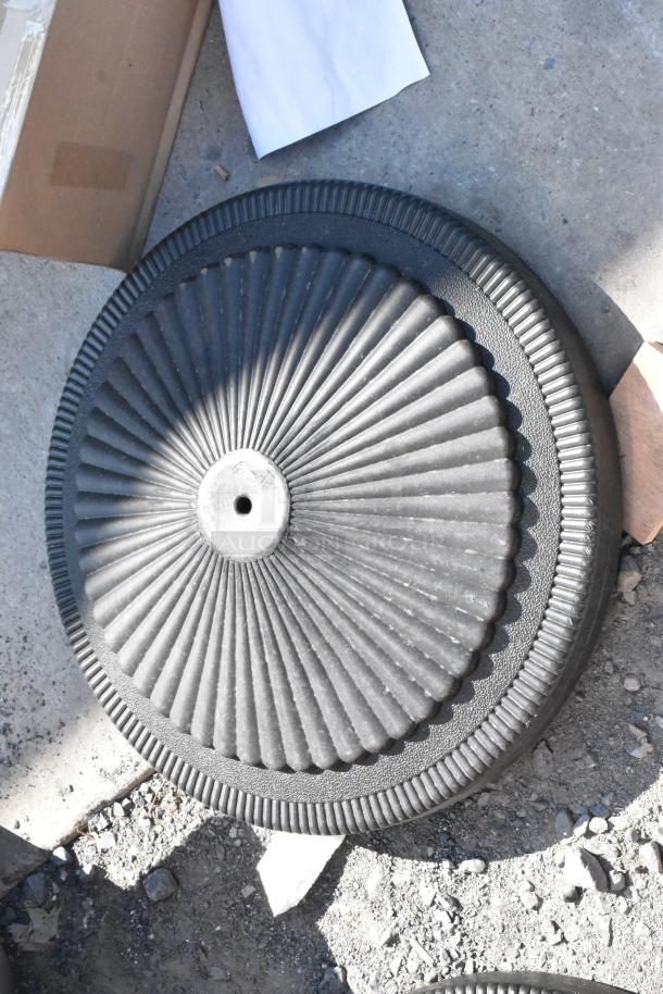 New black metal table base foot with textured radial design. Light scratches and dents visible. Bid includes two pieces.