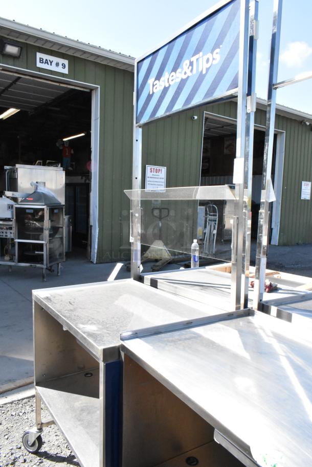 Stainless steel cart with under shelf on commercial casters, good condition, featuring "Tastes & Tips" signage.