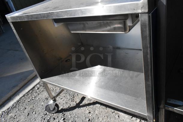 Stainless steel cart with under shelf, on commercial casters, showing a sturdy build and used condition.