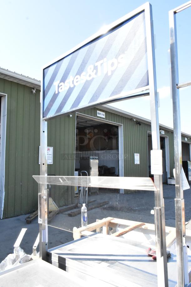 Stainless steel cart with under shelf, and commercial casters, featuring a "Tastes & Tips" sign, in good condition.