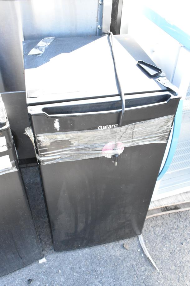 Two Galanz GLR33MBKE23 mini coolers, 120 volts, 1 phase, black, visible wear with tape and scratches, power cable shown.