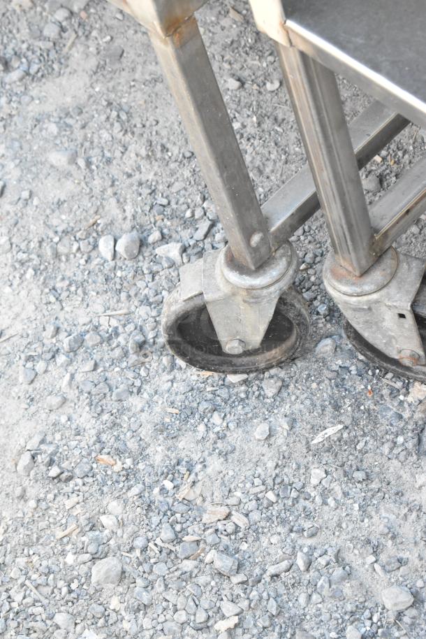 Stainless steel cart with under shelf on sturdy commercial casters. Durable construction, ideal for industrial use.