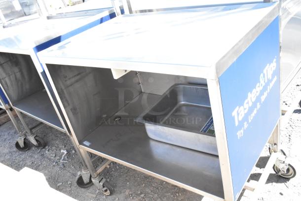 Stainless steel cart with under shelf, on commercial casters, features side panel with "Tastes & Tips" branding.