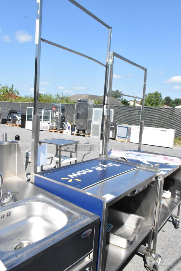 Stainless steel cart with under shelf, commercial casters, built-in sink, and signage frame. Good condition.