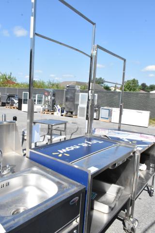 Stainless steel cart with under shelf, commercial casters, built-in sink, and signage frame. Good condition.