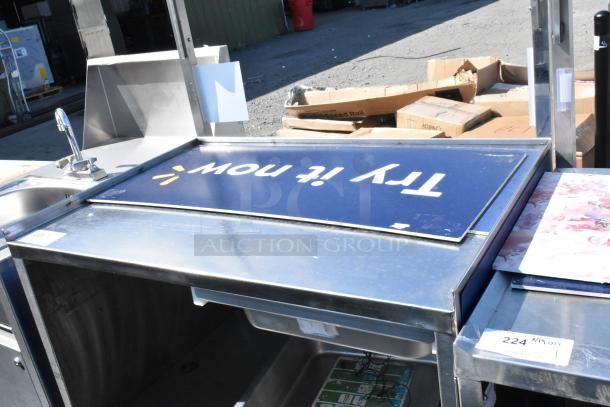 Stainless steel cart with under shelf on commercial casters, featuring a faucet and a "Try it now" sign, in good condition.