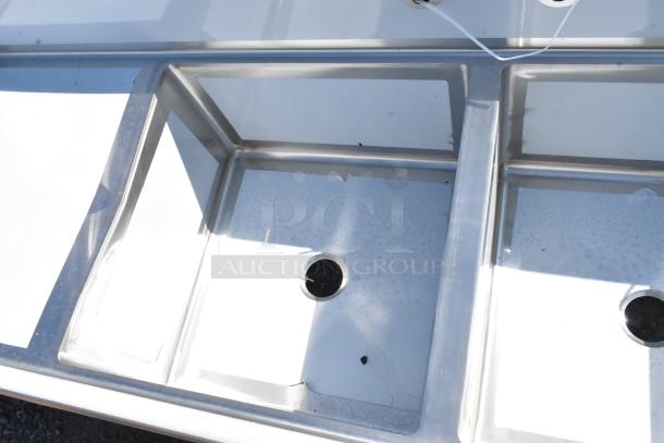 New Regency 600S3242424S stainless steel three-compartment commercial sink with two drainboards, minor scratches visible.