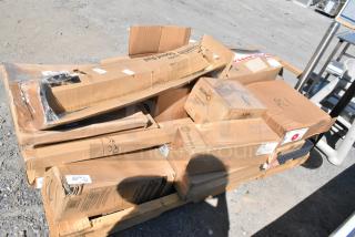 Boxes of brand new scratch and dent items, including trash can dolly, wine glasses, and food storage containers, on a pallet.