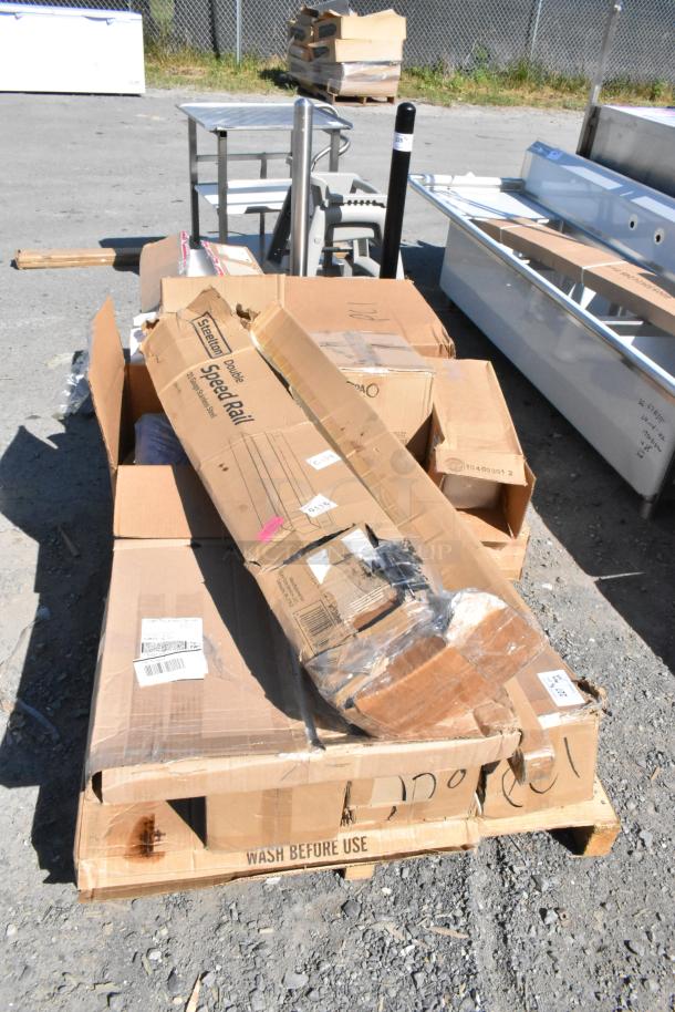 Brand new scratch and dent items on a pallet, including a trash can dolly and food storage containers, boxed and labeled.