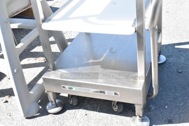 Stainless steel meat slicer equipment stand on commercial casters, two shelves, visible brand sticker, good condition.
