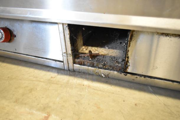Stainless steel commercial countertop griddle with thermostatic controls. Moderate wear, visible grime inside under heating elements.