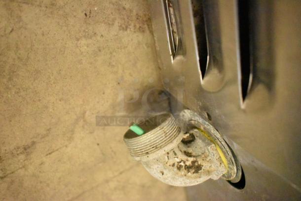 Stainless steel commercial countertop flat top griddle. Close-up of gas inlet, slight wear visible.