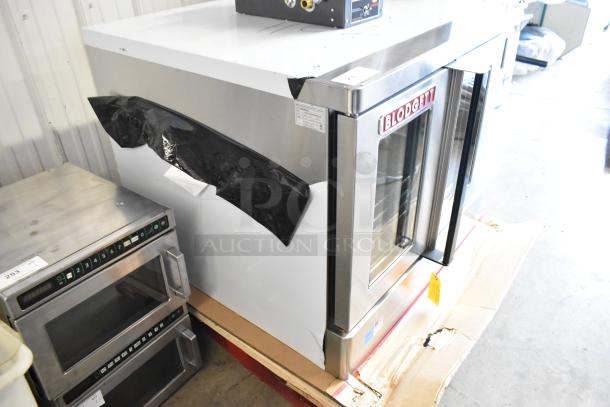 Brand new Blodgett Zephaire-200-E stainless steel convection oven with view-through doors, thermostatic controls, and metal racks; minor dents visible.
