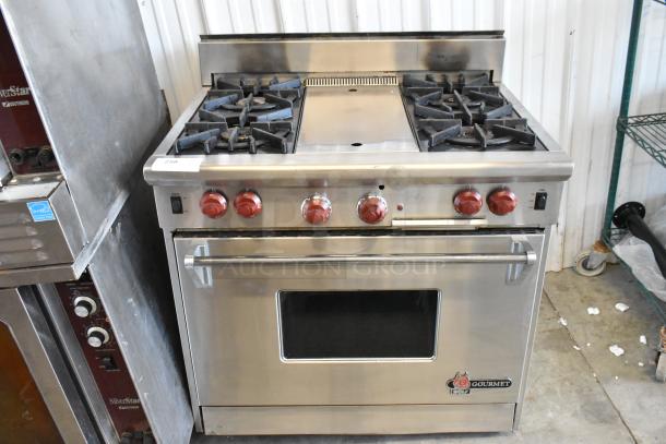 Wolf Gourmet stainless steel 4-burner gas range with center flat top and convection oven. Features red knobs, logo visible.