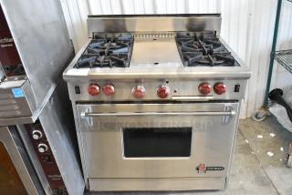 Wolf Gourmet stainless steel 4-burner gas range with center flat top and convection oven. Features red knobs, logo visible.