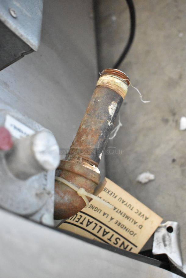 Close-up of Wolf Gourmet 4-Burner Range pipe and installation tag, indicating components and condition.