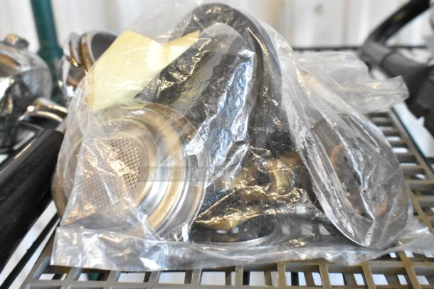 Lot of espresso machine items including portafilters in plastic bag; various metal parts visible; items appear used.