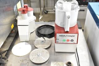 Brand new Robot Coupe R2 food processor, 3 Qt gray bowl, continuous feed, 3 blades, 120V, 1 Phase, slight dents visible.