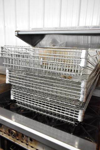 Seven metal wire basket-style shelves, stacked, in good condition. Ideal for storage, industrial use.