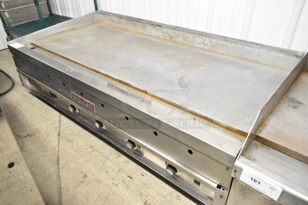 Vulcan stainless steel commercial countertop flat top griddle, featuring four control knobs. Some surface wear visible.