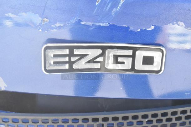 EZ Go blue and white 6-seat golf cart with visible speaker system, logo shown. Slight surface wear on blue finish.