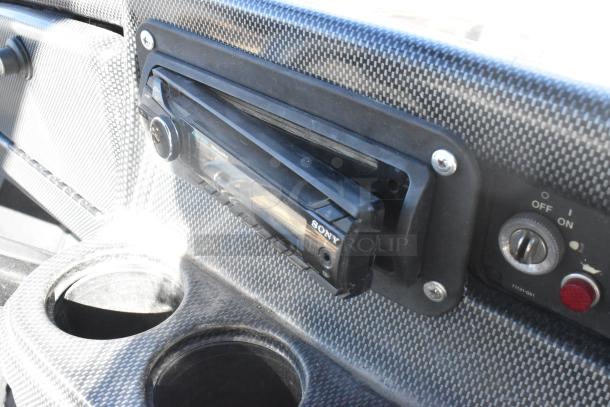 Close-up of EZ Go golf cart interior showing Sony marine speaker system, carbon fiber-style panel, cup holders, and controls.