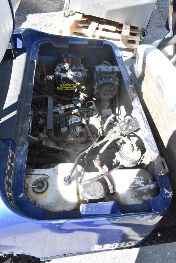 Blue and white EZ Go 6-seat golf cart with speaker system, showing under seat battery compartment. Visible wear and component details.